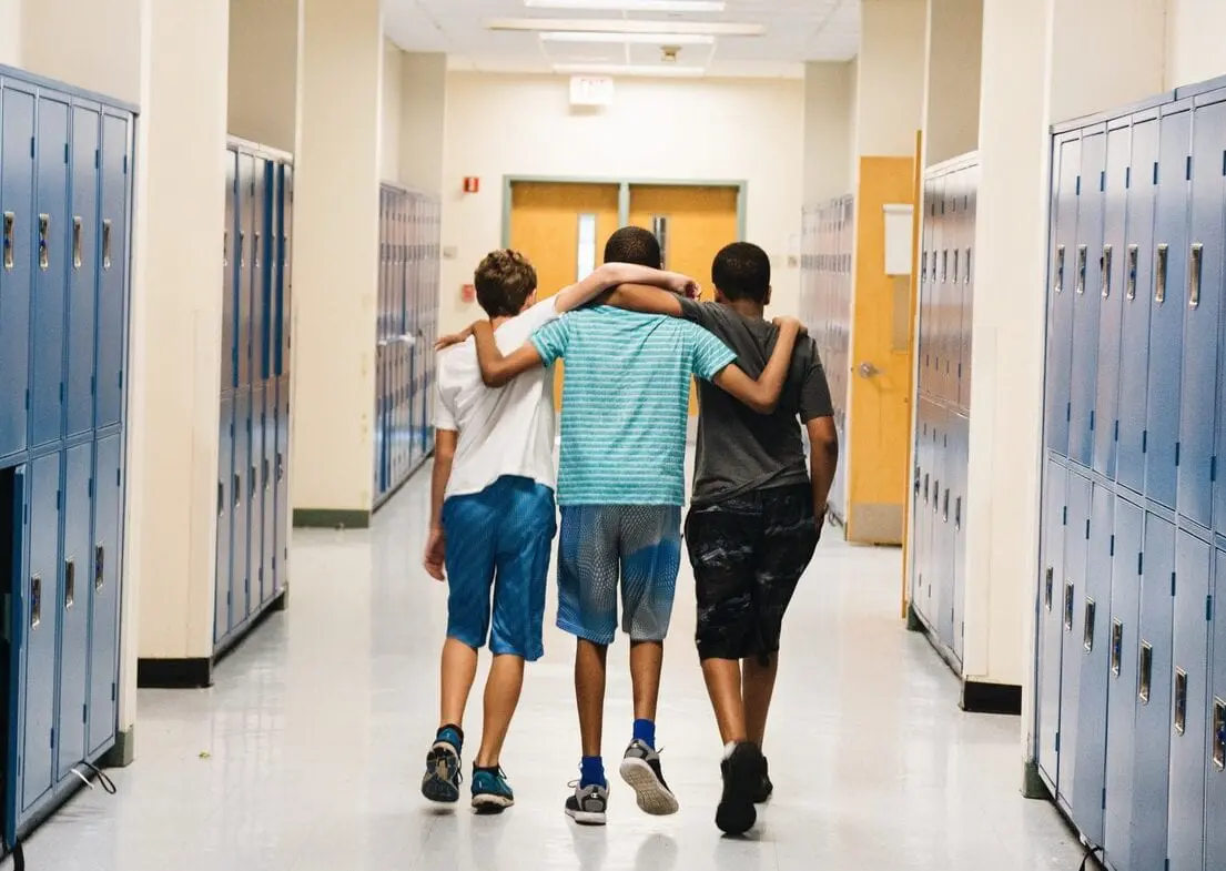 Bryan Bailey (right) and friends walk down the hallway arm in arm.
